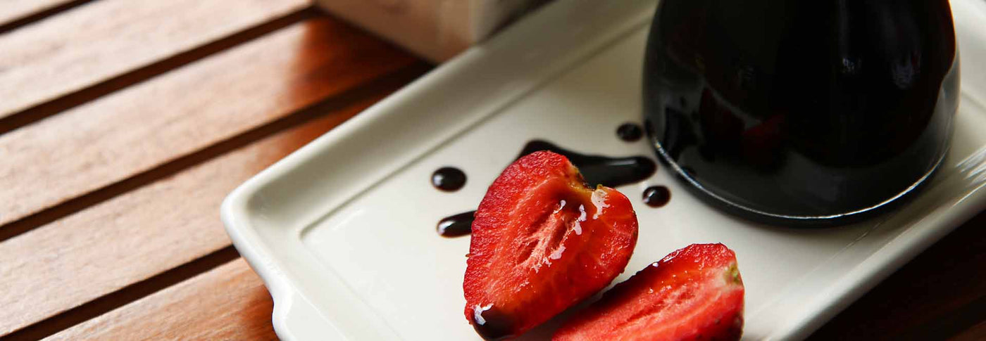 Balsamic vinegar drizzled over sliced strawberries on plate