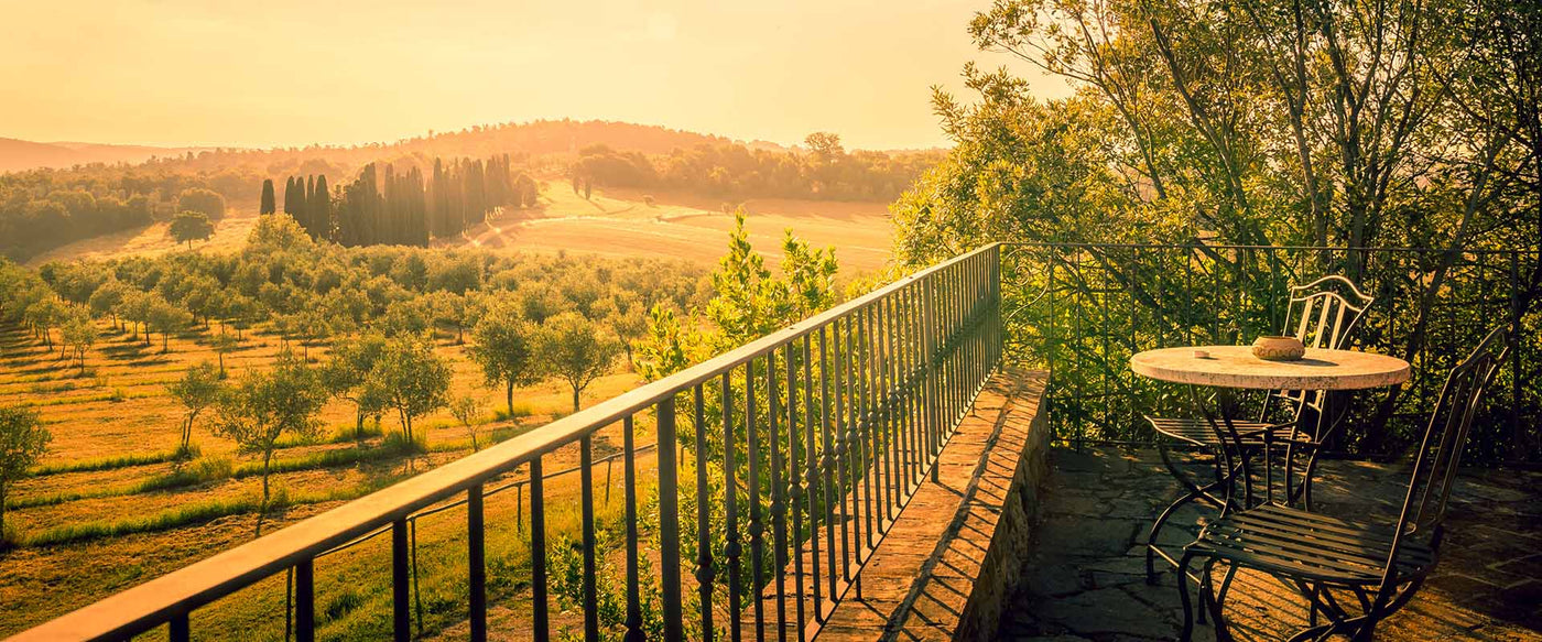 Two chairs on a balcony overlooking the Italian country side during golden hour